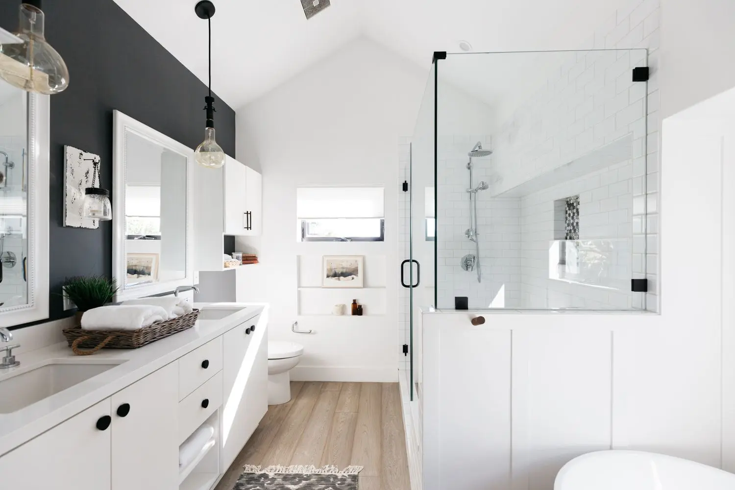Remodeled bathroom with a glass walk-in shower, double vanity, and vaulted ceiling