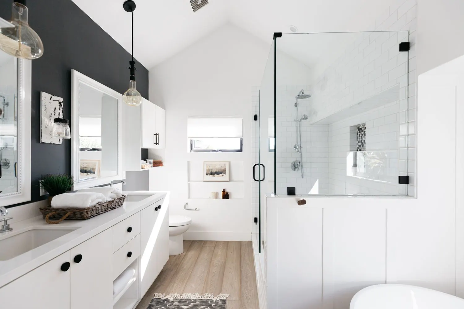 Remodeled bathroom with a glass walk-in shower, double vanity, and vaulted ceiling