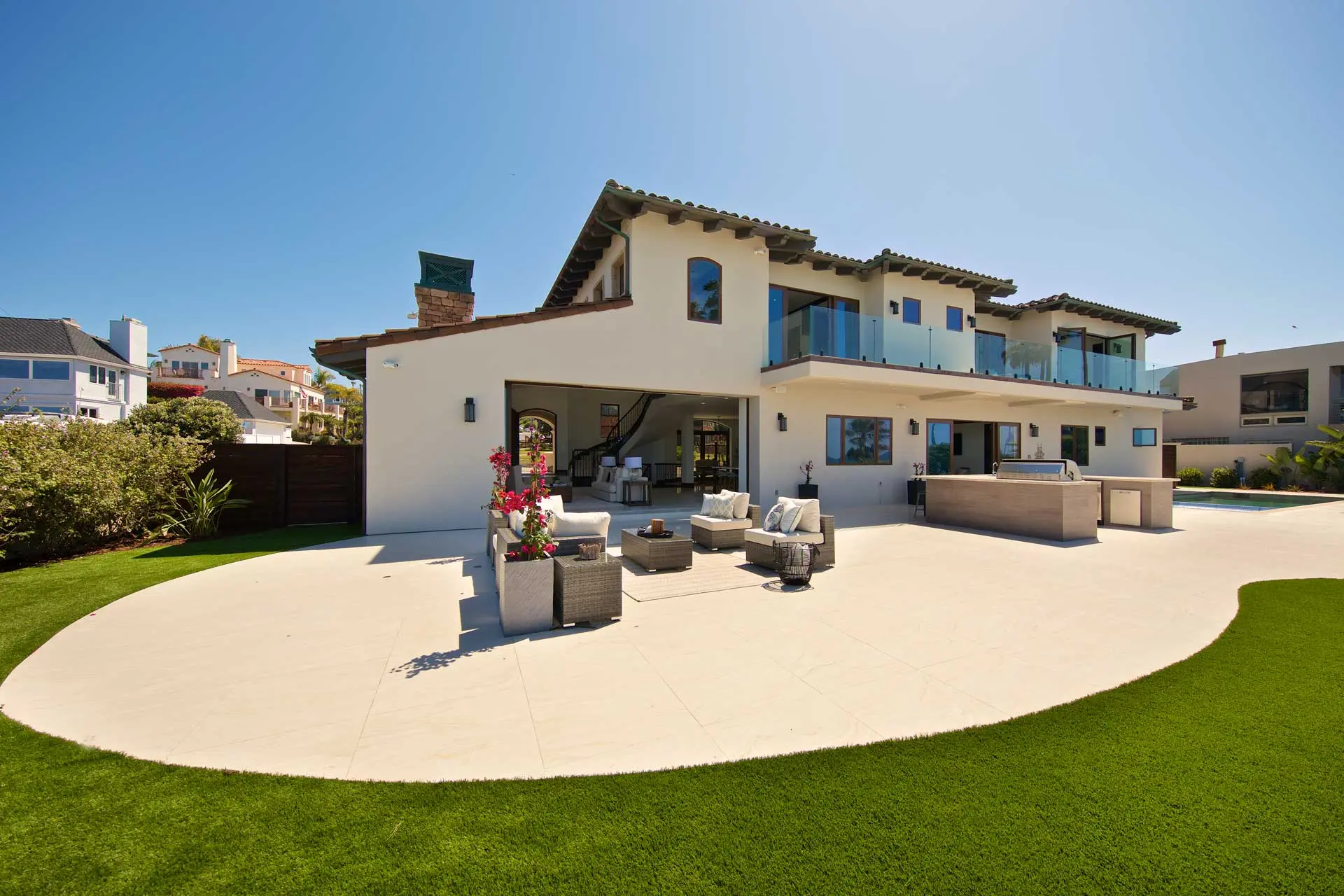 Finished custom home exterior with a covered lower-level patio opening onto lawn