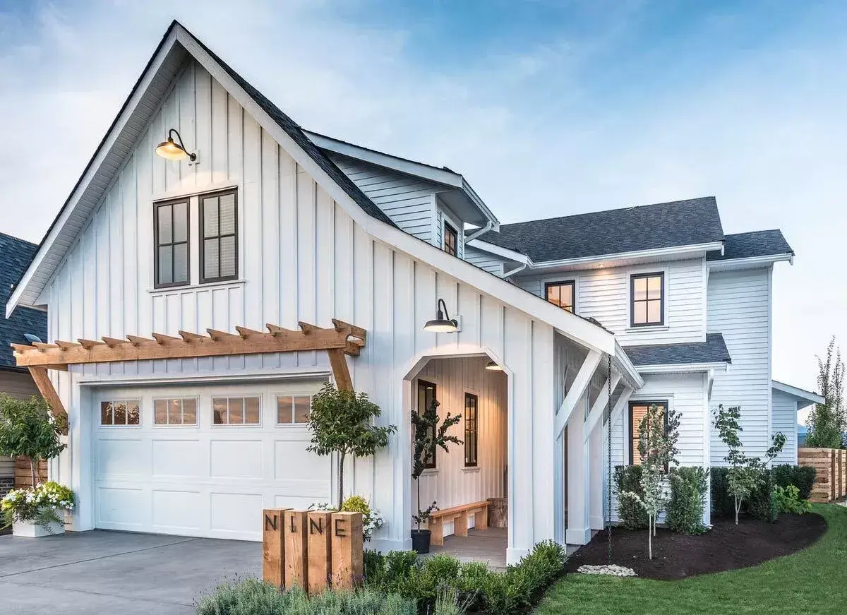 Modern farmhouse custom home in Idaho with board-and-batten siding and a timber pergola at dusk