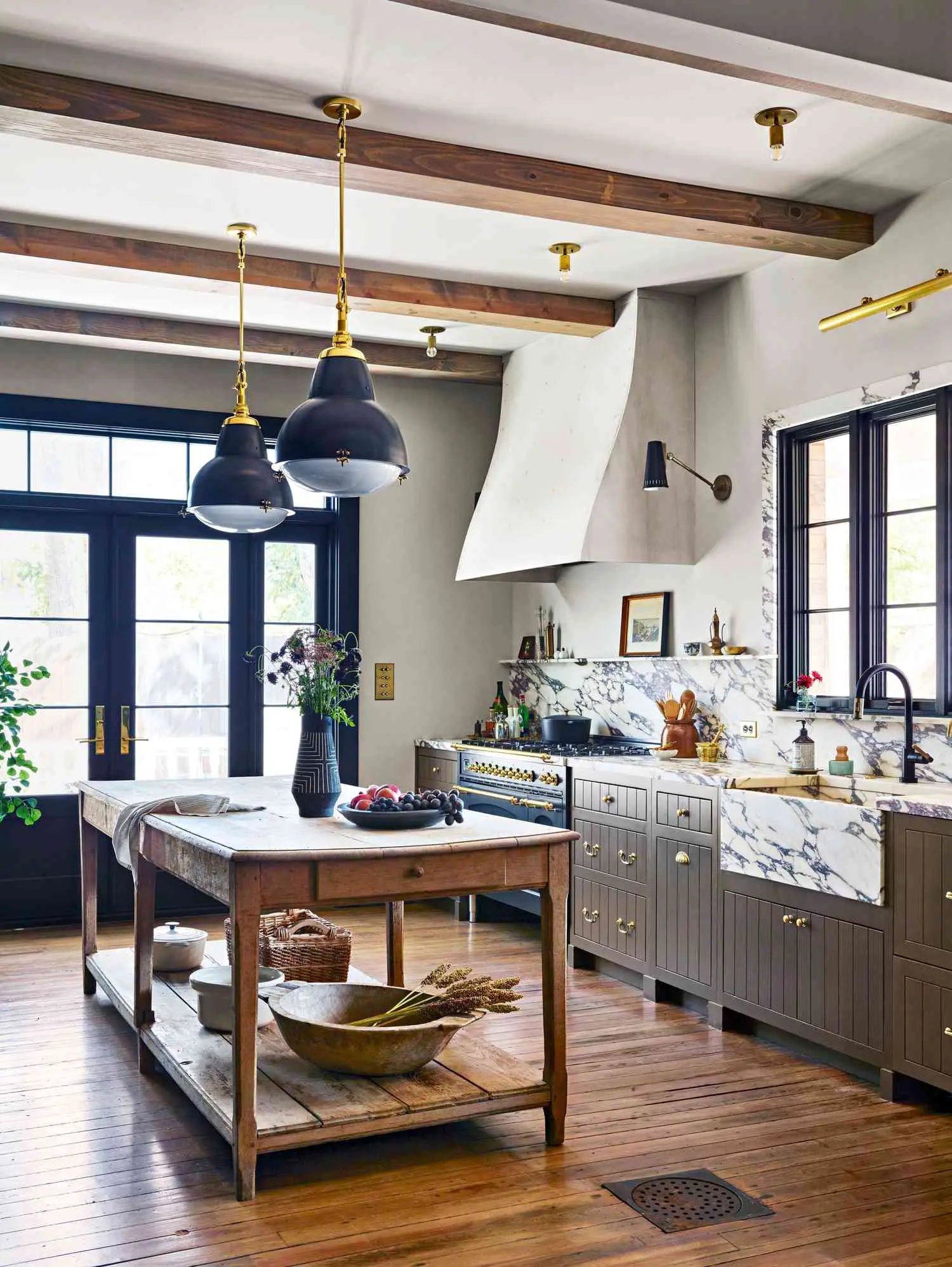Remodeled kitchen with exposed wood beams, marble counters, and a plaster range hood