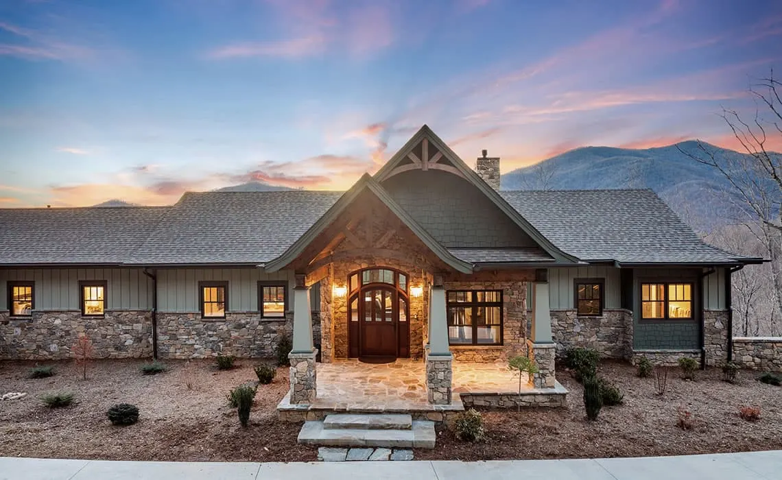 Custom home with timber entry and stone base built in the mountains at sunset
