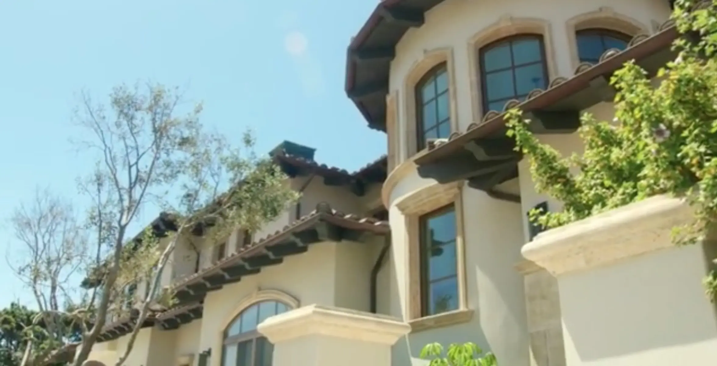 Detail of a finished building exterior with stucco, stone trim, and tile roofline